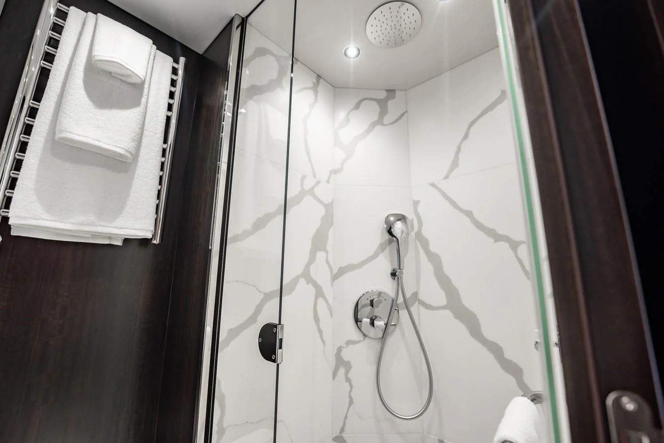 The yacht's bathroom features a modern shower with elegant marble-patterned walls and luxurious amenities. aboard BAZINGA Yacht for Sale
