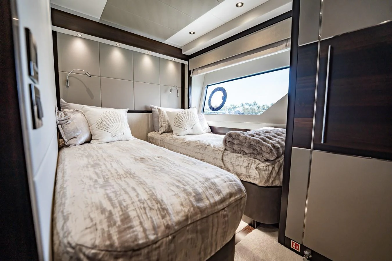 The guest stateroom features twin beds with luxurious bedding and a large window for natural light. aboard BAZINGA Yacht for Sale