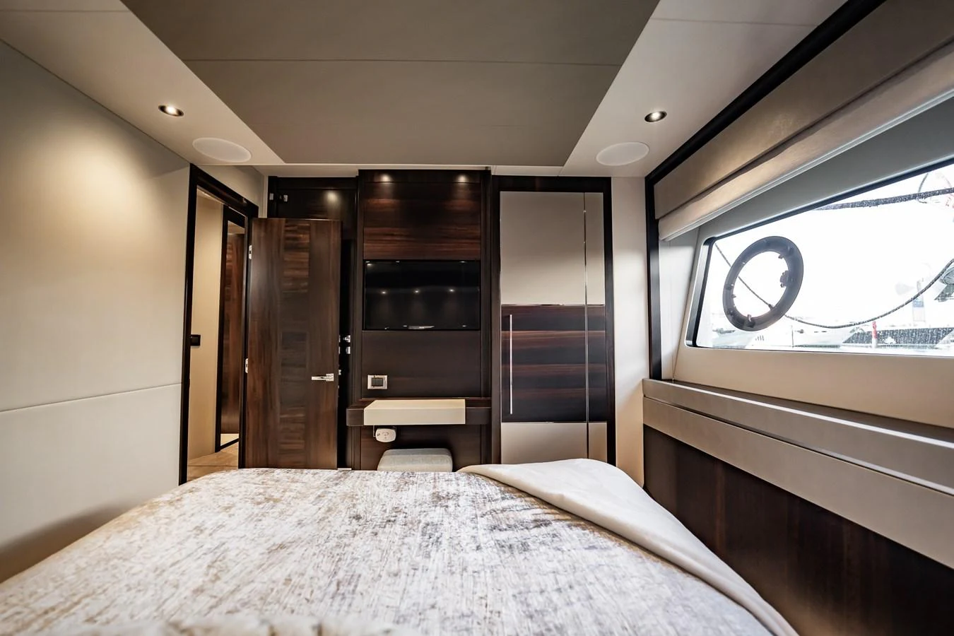 A luxurious stateroom featuring a comfortable bed, modern furnishings, and a large window with a view. aboard BAZINGA Yacht for Sale