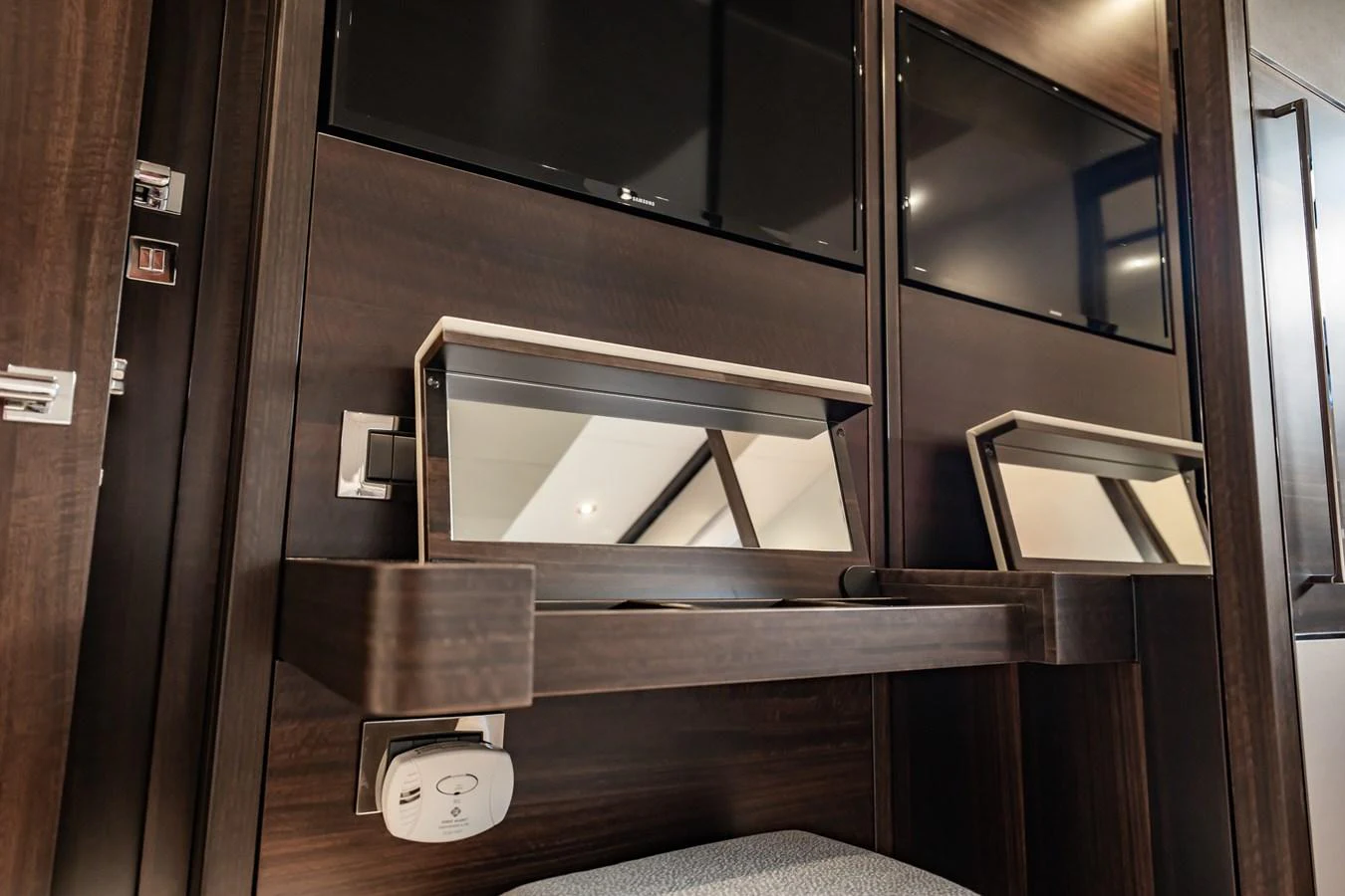 The image showcases a modern and sleek interior vanity area with dark wood finishes and built-in mirrors. aboard BAZINGA Yacht for Sale