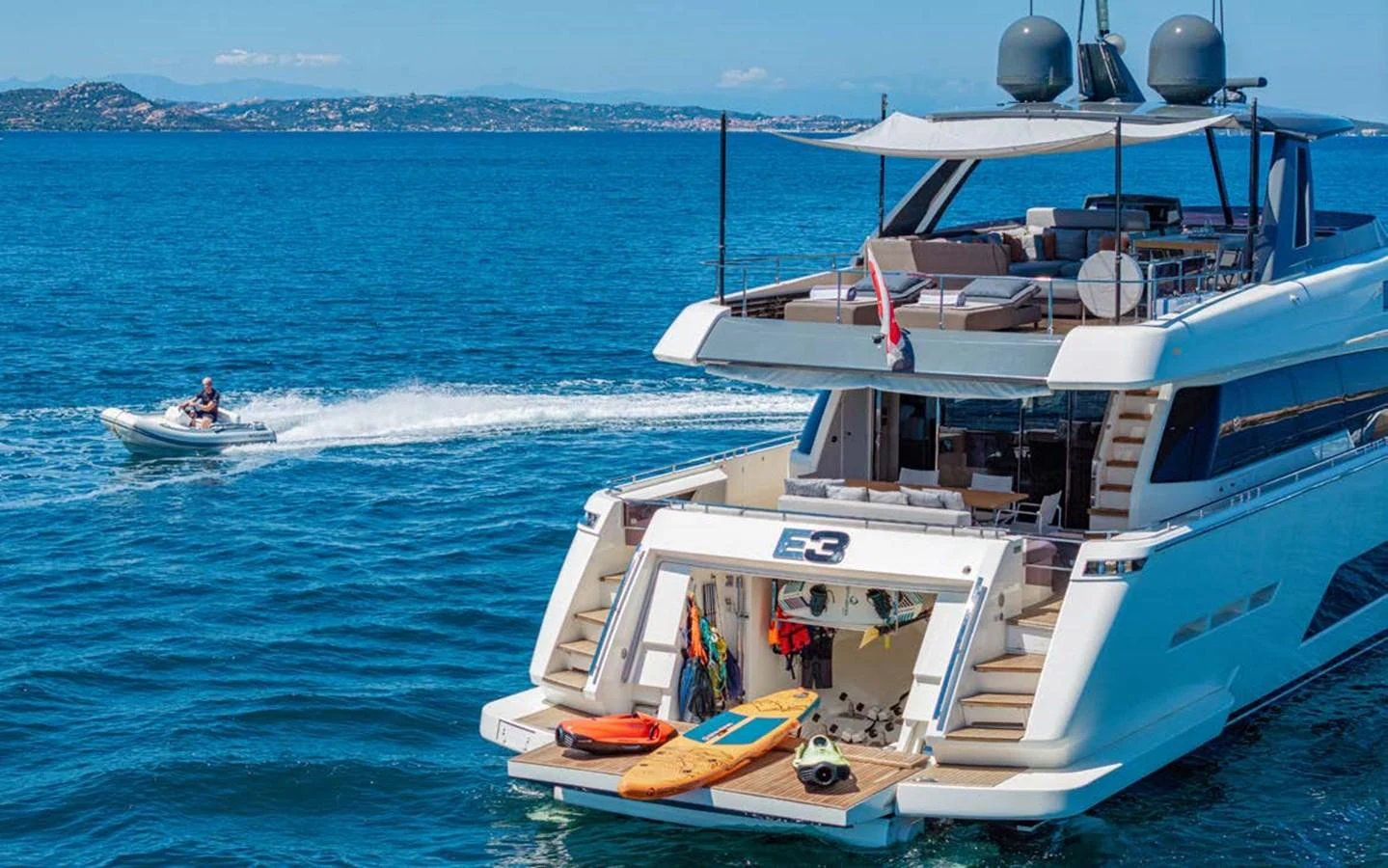 The yacht's aft deck features a spacious swim platform with water toys and a tender nearby. aboard E3 Yacht for Sale