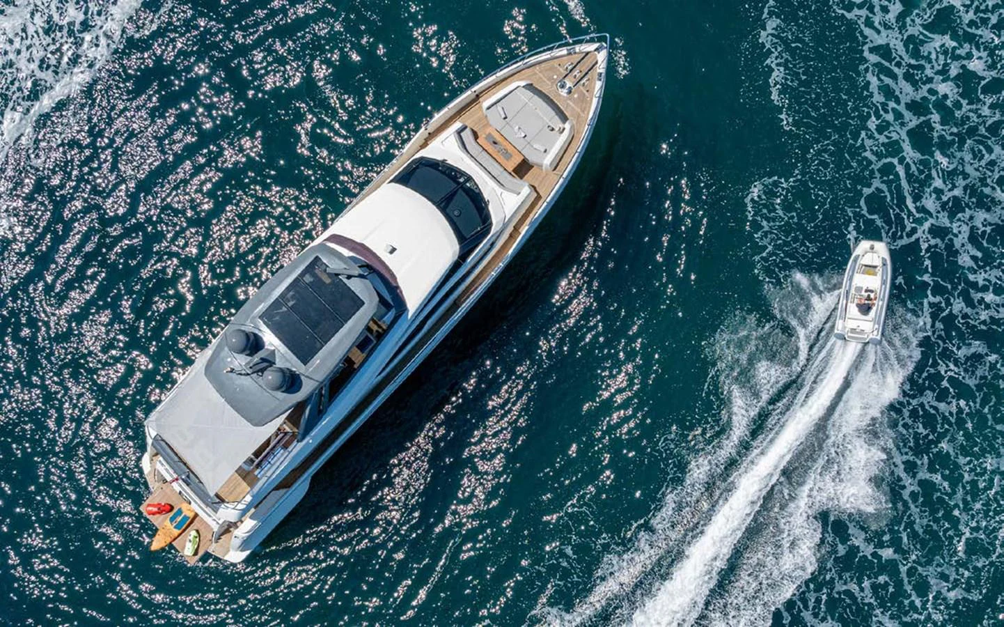 An aerial view of a luxurious yacht cruising on the open sea, accompanied by a smaller tender boat. aboard E3 Yacht for Sale