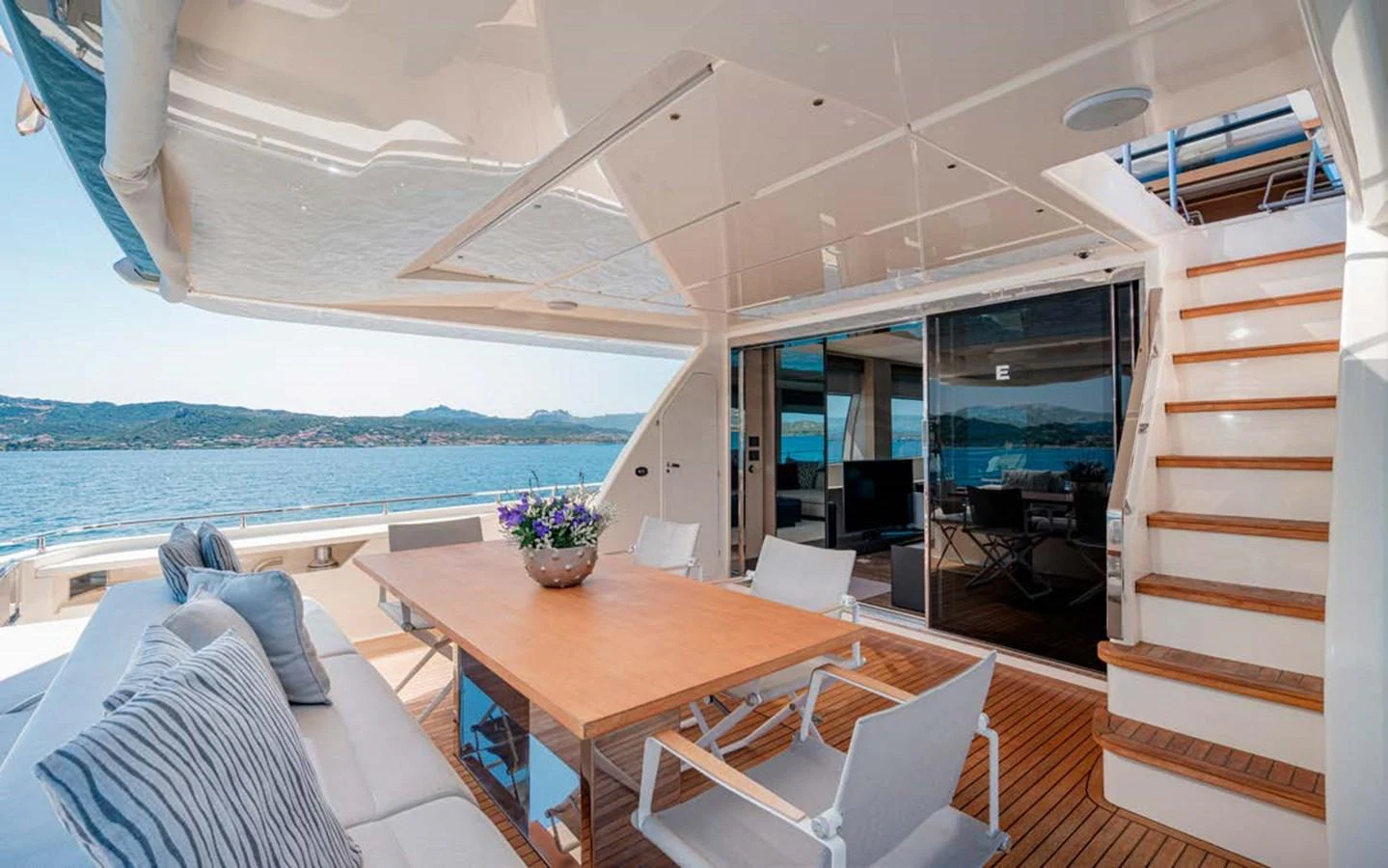The aft deck features a spacious dining area with a wooden table and comfortable seating, perfect for alfresco dining with a view of the water. aboard E3 Yacht for Sale