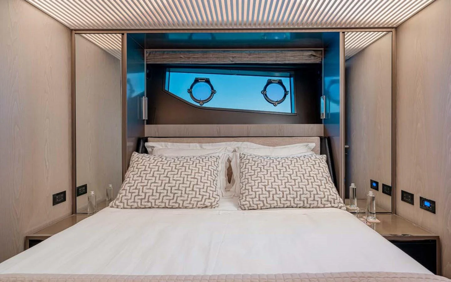 The stateroom features a plush bed with elegant bedding and a view through the porthole windows. aboard E3 Yacht for Sale