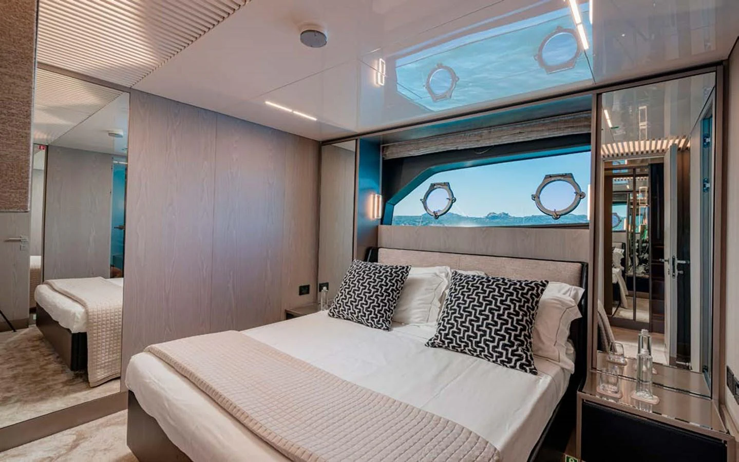 A luxurious stateroom featuring a comfortable bed with elegant bedding and a scenic view through the window. aboard E3 Yacht for Sale