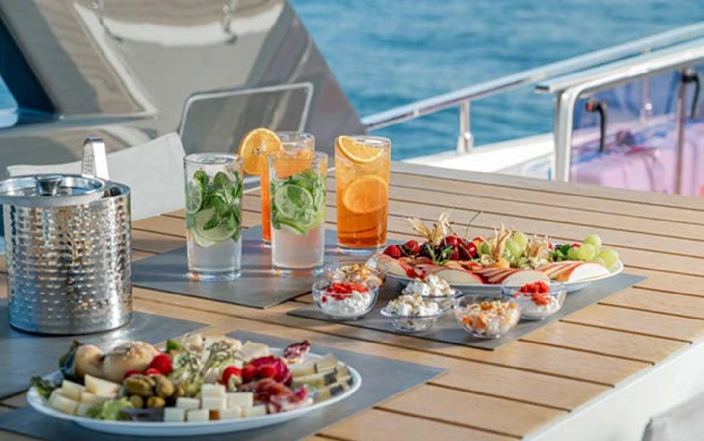 A beautifully arranged dining setup on the yacht's deck with refreshing drinks and appetizers. aboard E3 Yacht for Sale