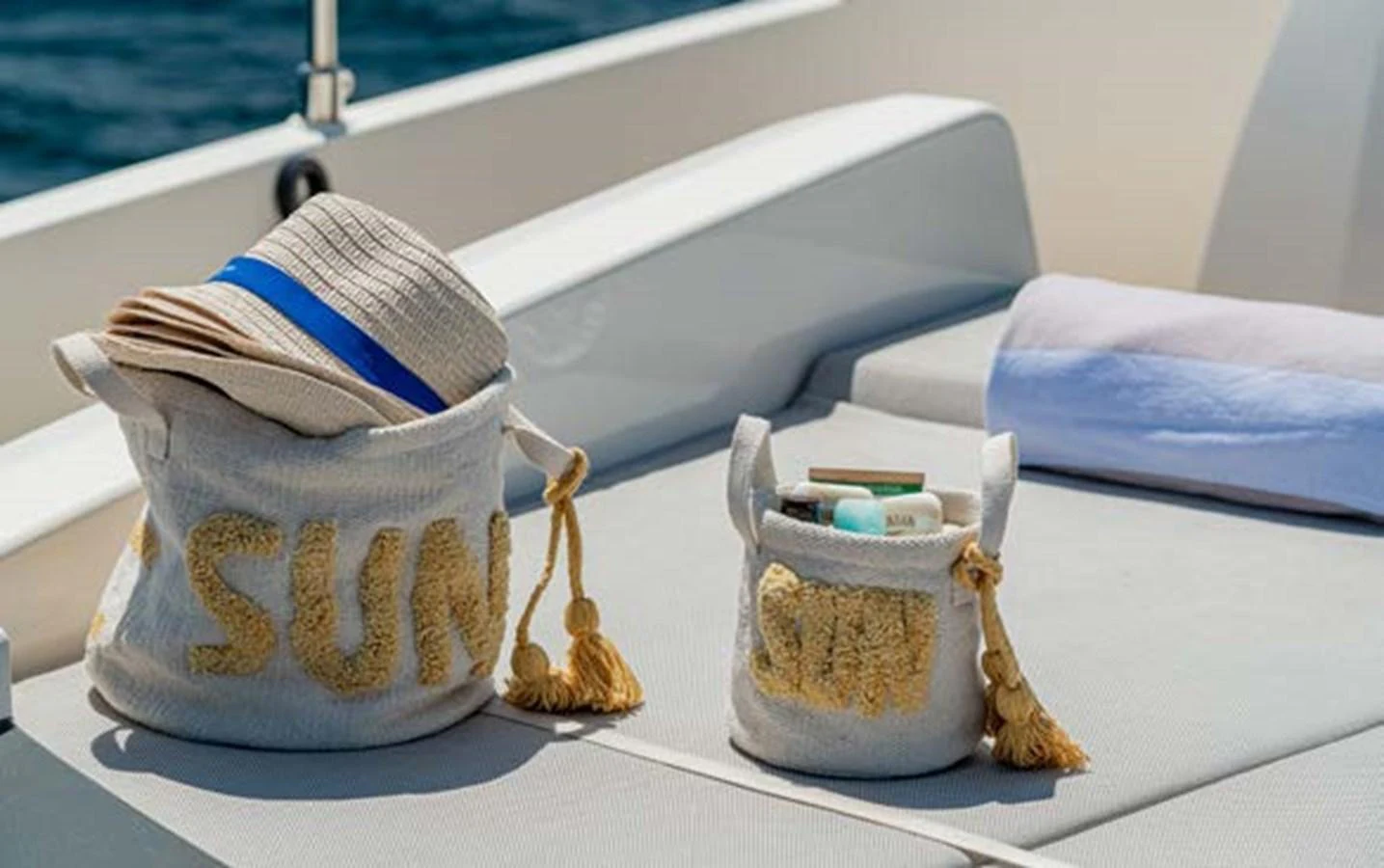 A close-up of sun hats and sunscreen in stylish bags on a sunbed, perfect for a sunny day at sea. aboard E3 Yacht for Sale