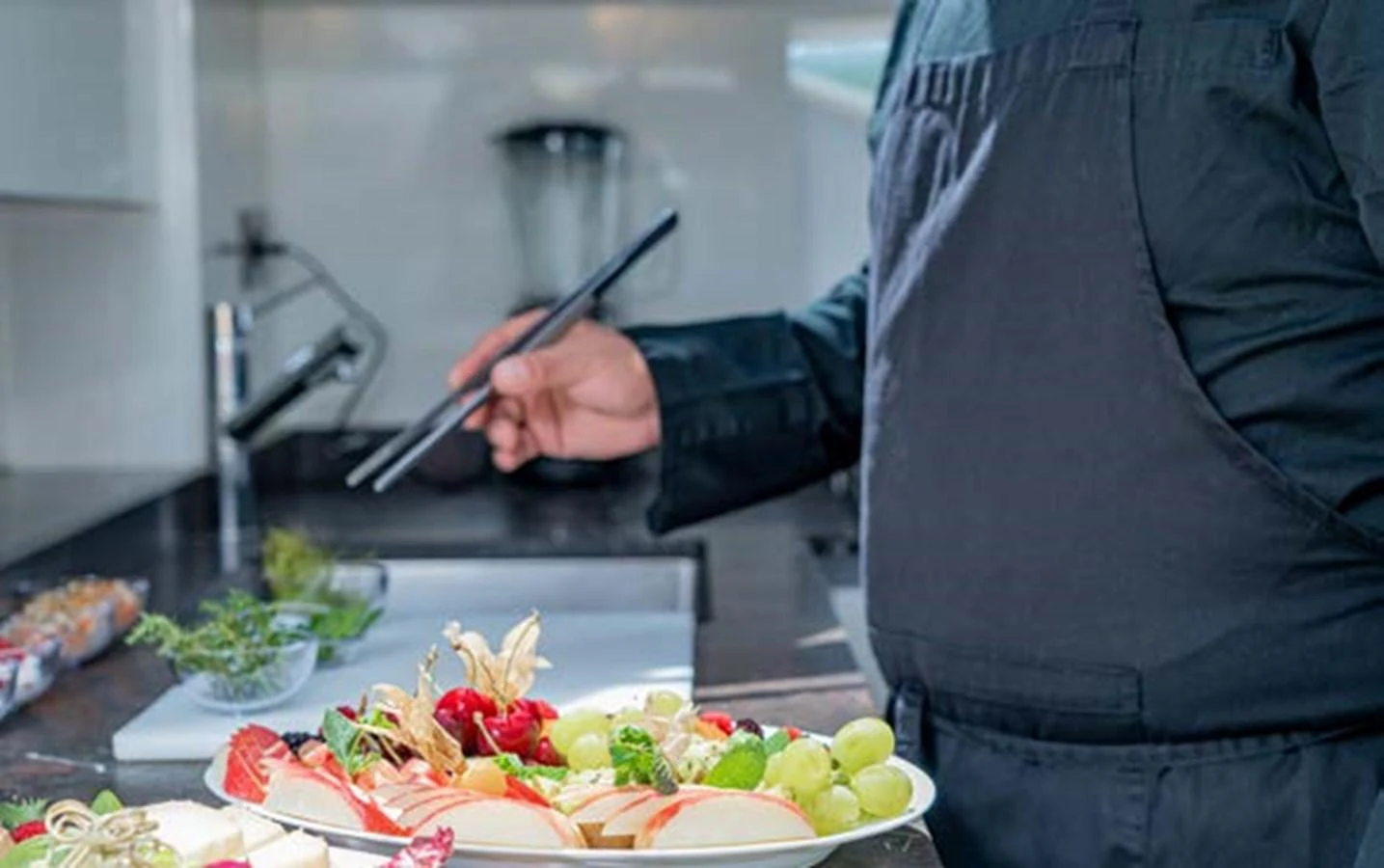 A chef prepares a beautifully arranged platter of fresh fruits and vegetables in the yacht's galley. aboard E3 Yacht for Sale