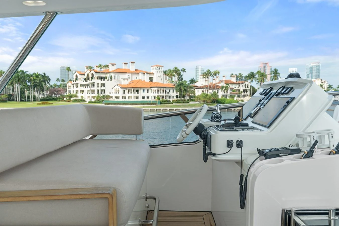 The helm station offers a comfortable seating area with advanced navigation equipment, overlooking a scenic waterfront view. aboard AZIMUT GRANDE 32/23 Yacht for Sale