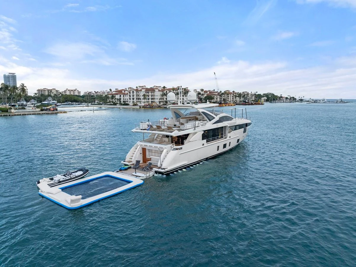 A luxurious yacht anchored in a serene harbor, featuring an attached floating pool and tender. aboard AZIMUT GRANDE 32/23 Yacht for Sale
