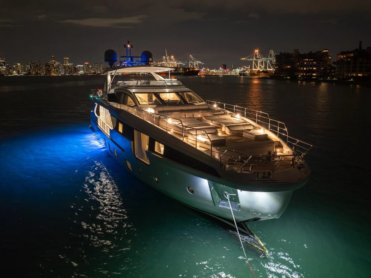 A luxurious yacht is beautifully illuminated at night, showcasing its sleek design and elegant lighting against a cityscape backdrop. aboard AZIMUT GRANDE 32/23 Yacht for Sale