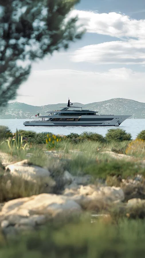 The yacht is gracefully anchored in a serene bay, surrounded by lush greenery and distant hills. aboard BAGLIETTO T54 Yacht for Sale