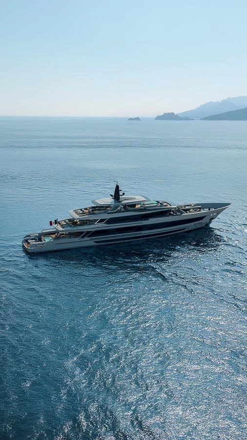 A luxurious yacht cruises through serene blue waters with distant mountains in the background. aboard BAGLIETTO T54 Yacht for Sale