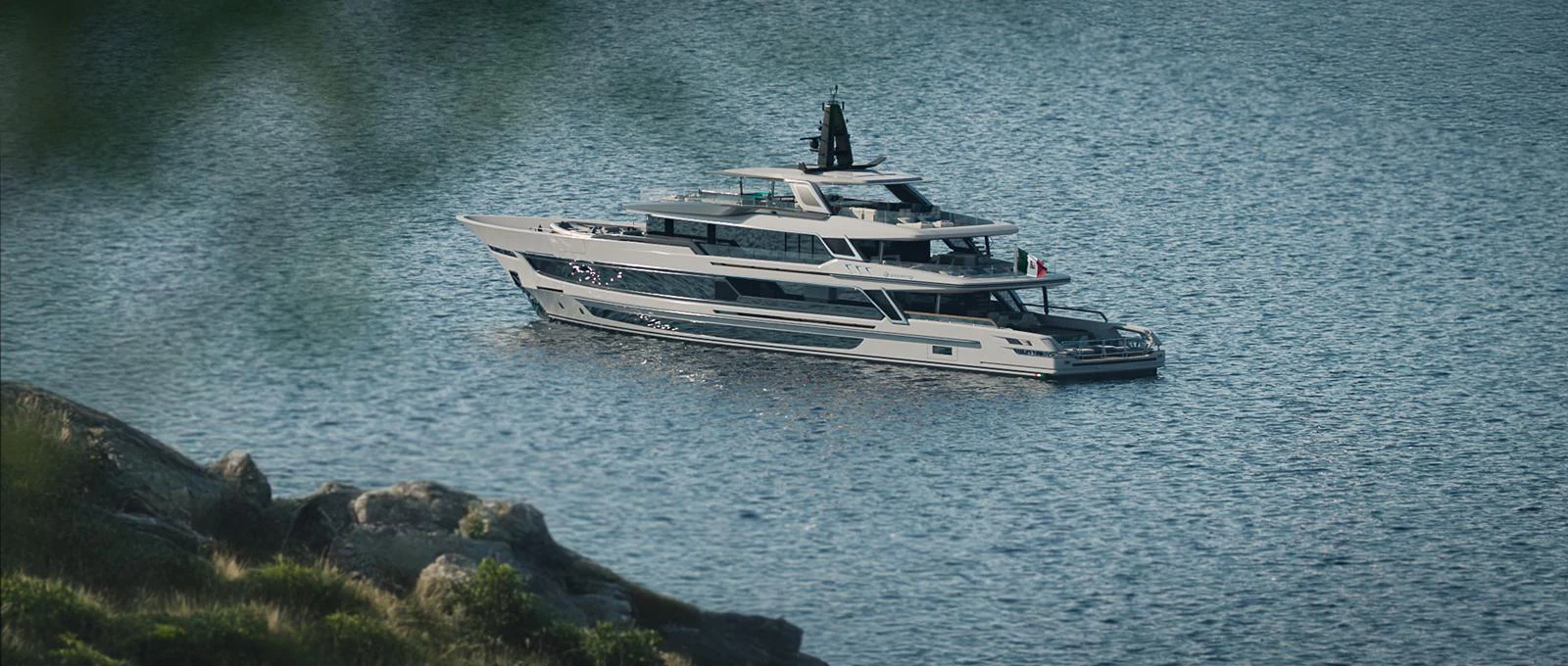 A sleek and modern yacht is anchored in calm waters near a rocky shoreline. aboard BAGLIETTO T54 Yacht for Sale