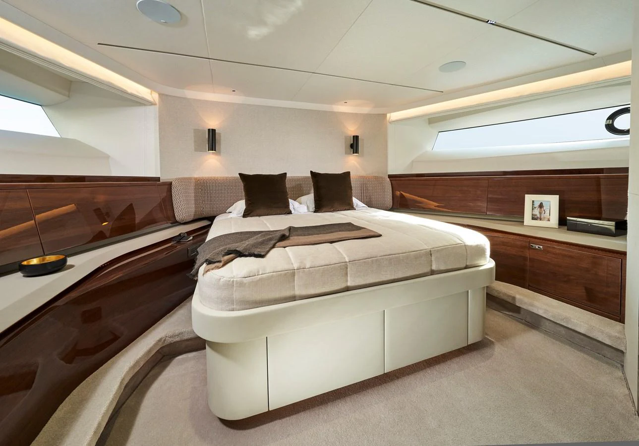 The stateroom features a luxurious bed with elegant wood paneling and ample natural light. aboard PRINCESS X95 VISTA Yacht for Sale