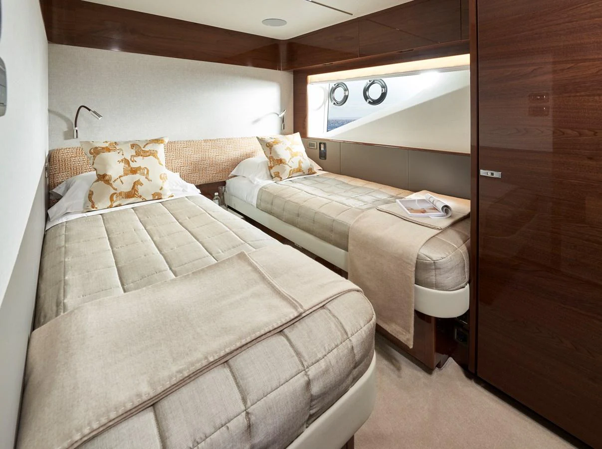 The twin stateroom features two single beds with elegant bedding and a warm, inviting atmosphere. aboard PRINCESS X95 VISTA Yacht for Sale