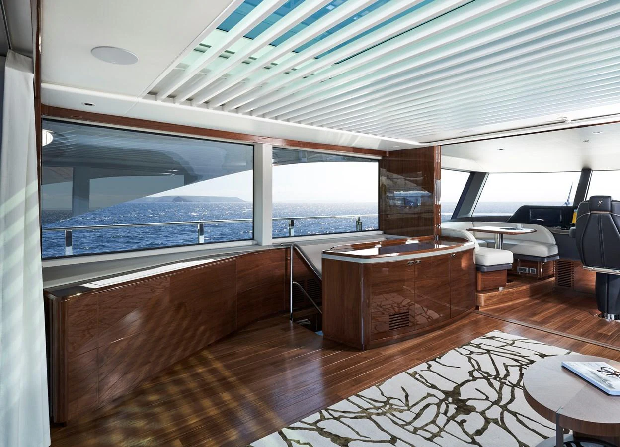 The salon features expansive windows with a stunning ocean view, luxurious wood finishes, and modern furnishings. aboard PRINCESS X95 VISTA Yacht for Sale