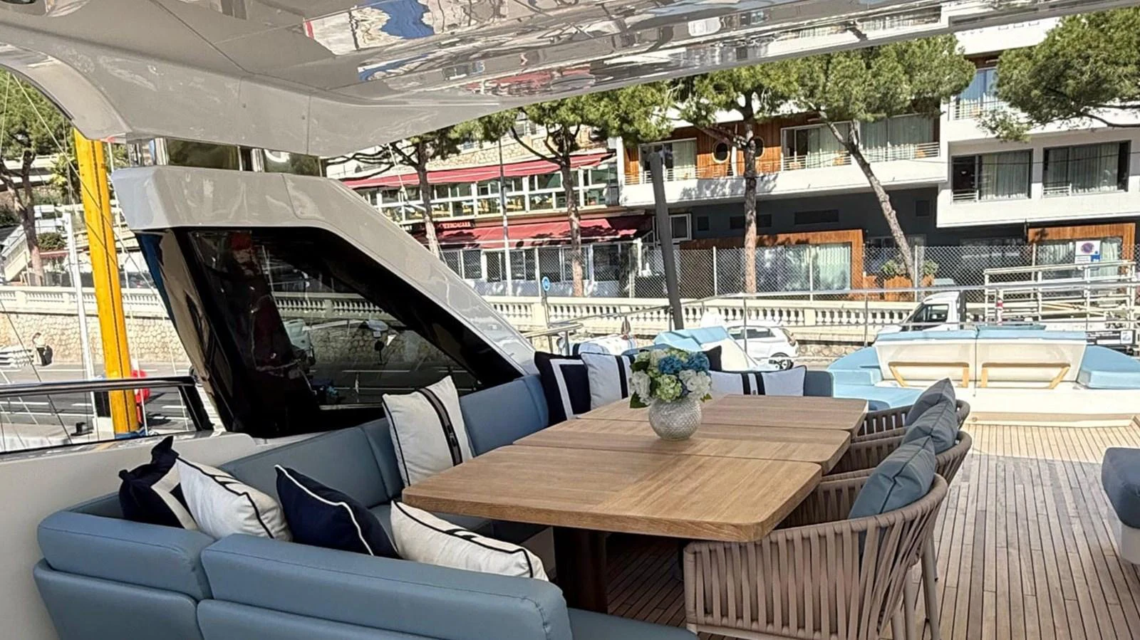 The aft deck features a spacious seating area with a large wooden dining table, perfect for alfresco dining. aboard ADROMELIA Yacht for Sale
