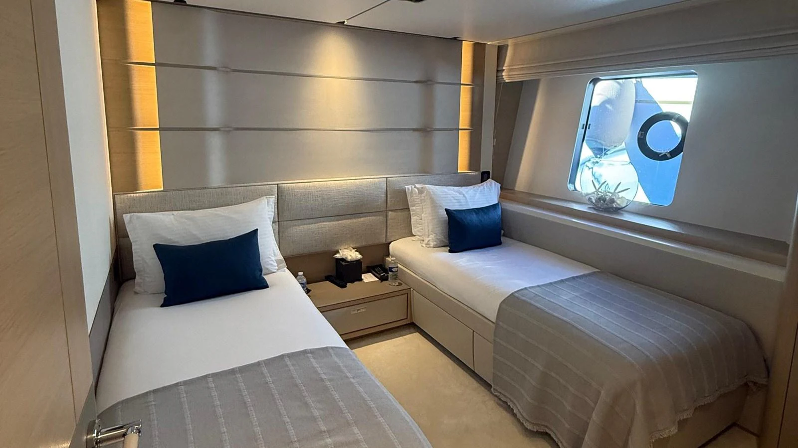 A cozy twin stateroom with modern decor and ample natural light from the window. aboard ADROMELIA Yacht for Sale