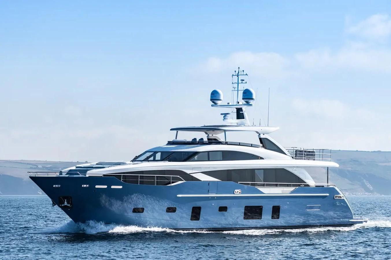 A sleek and modern yacht cruising on calm waters with a scenic coastal backdrop. aboard ADROMELIA Yacht for Sale