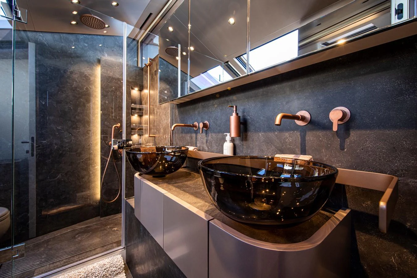 The yacht's bathroom features modern fixtures with dual glass sinks and a spacious shower area. aboard SEVEN Yacht for Sale