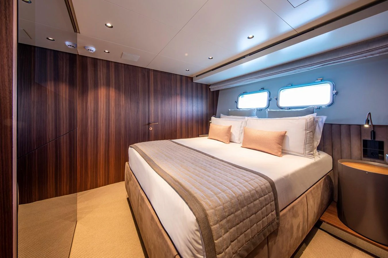 The stateroom features a luxurious bed with elegant wood paneling and ample natural light from the windows. aboard SEVEN Yacht for Sale