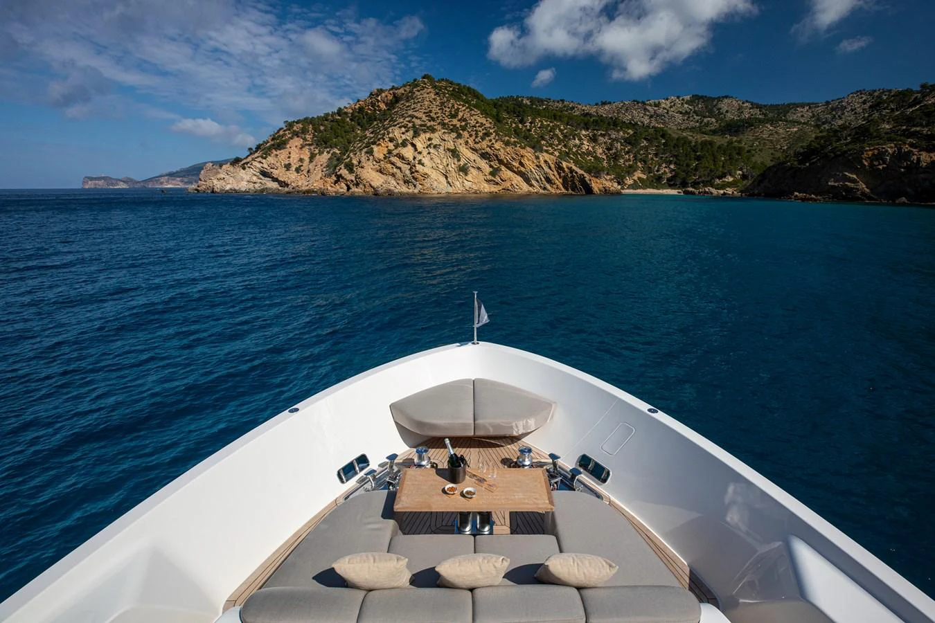 The yacht's bow offers a serene and inviting space with plush seating and a table, perfect for enjoying the scenic coastal views. aboard SEVEN Yacht for Sale