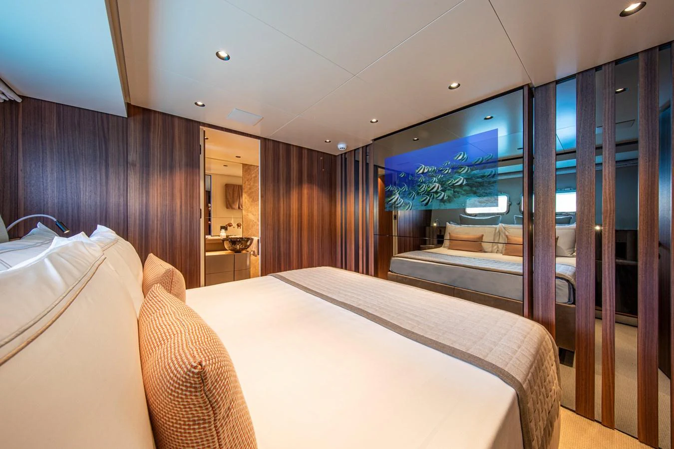 The master stateroom features a luxurious bed, elegant wood paneling, and an en-suite bathroom. aboard SEVEN Yacht for Sale