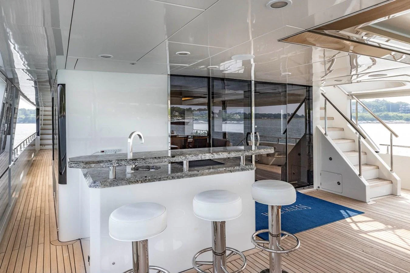 The aft deck features a sleek bar area with modern stools and a view of the water. aboard WRECKLESS Yacht for Sale