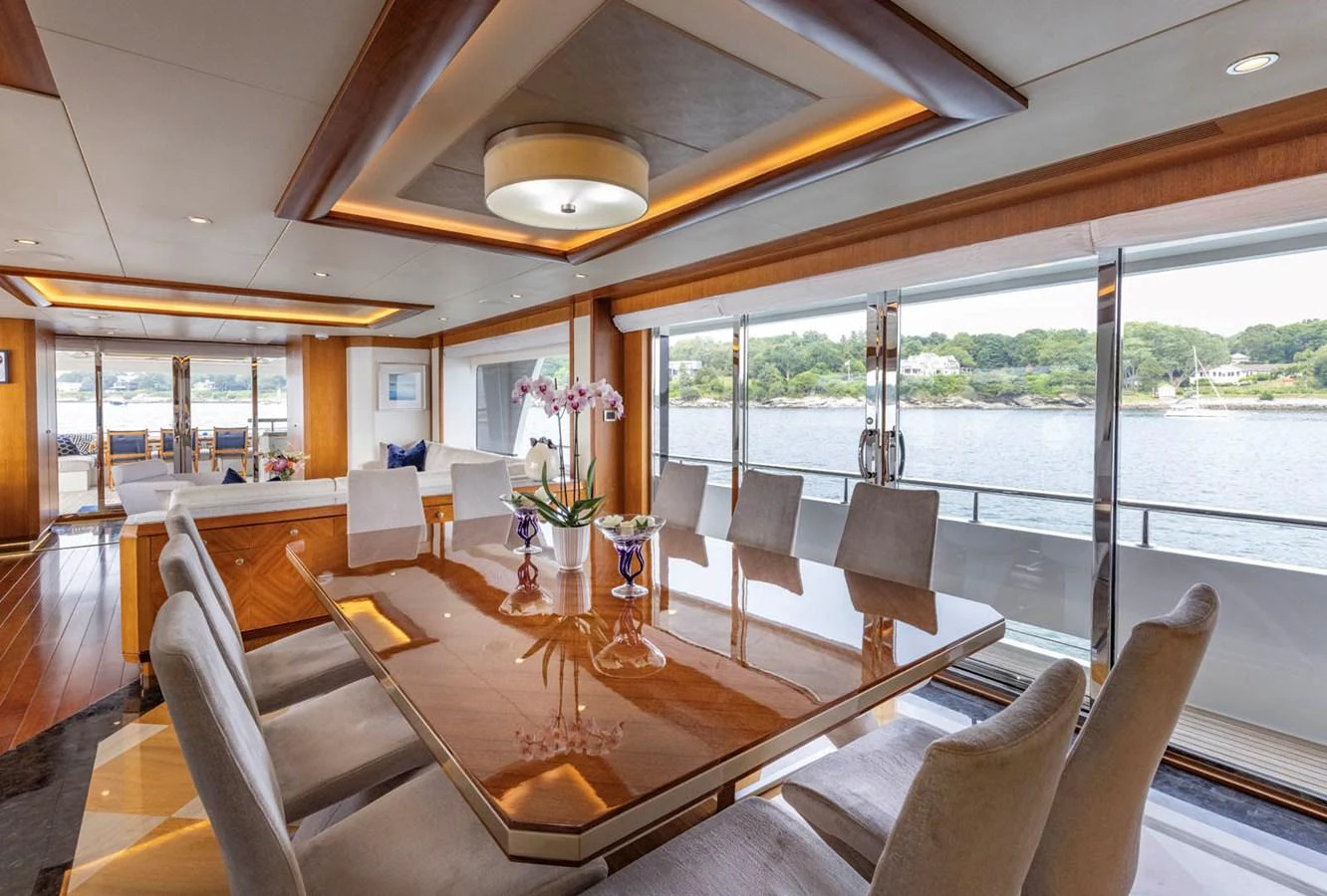 The yacht's dining area features a large polished table with comfortable seating and panoramic views through expansive windows. aboard WRECKLESS Yacht for Sale