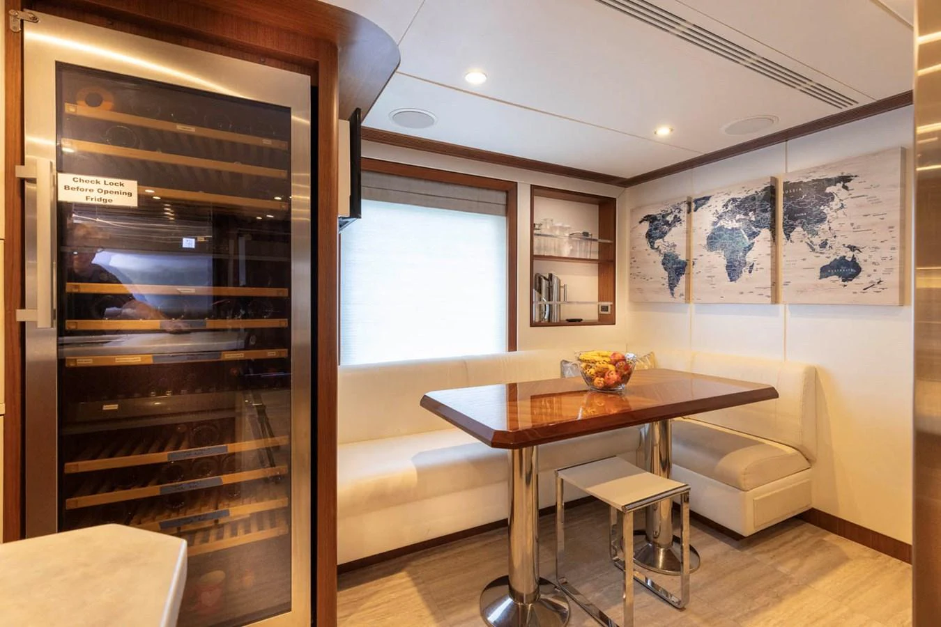 The yacht's dining area features a cozy seating arrangement with a wooden table and a large wine cooler. aboard WRECKLESS Yacht for Sale
