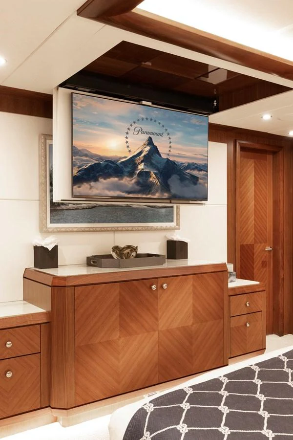 The stateroom features elegant wood cabinetry and a retractable television for a luxurious experience. aboard WRECKLESS Yacht for Sale