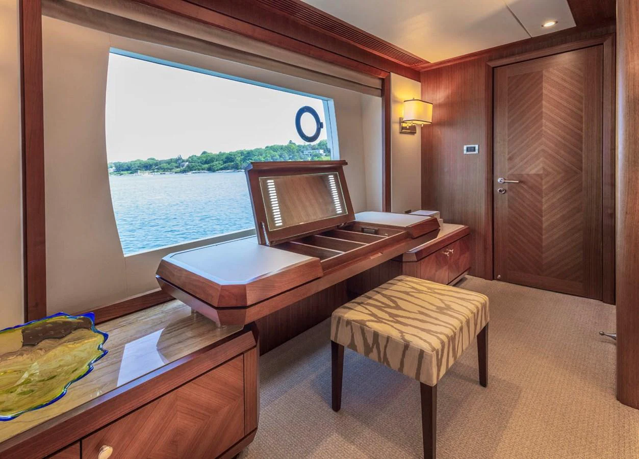 A luxurious interior space featuring elegant wooden furniture and a large window with a view of the water. aboard WRECKLESS Yacht for Sale