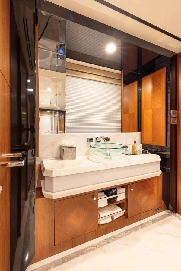 The yacht's bathroom features elegant wood paneling and a modern glass sink. aboard WRECKLESS Yacht for Sale