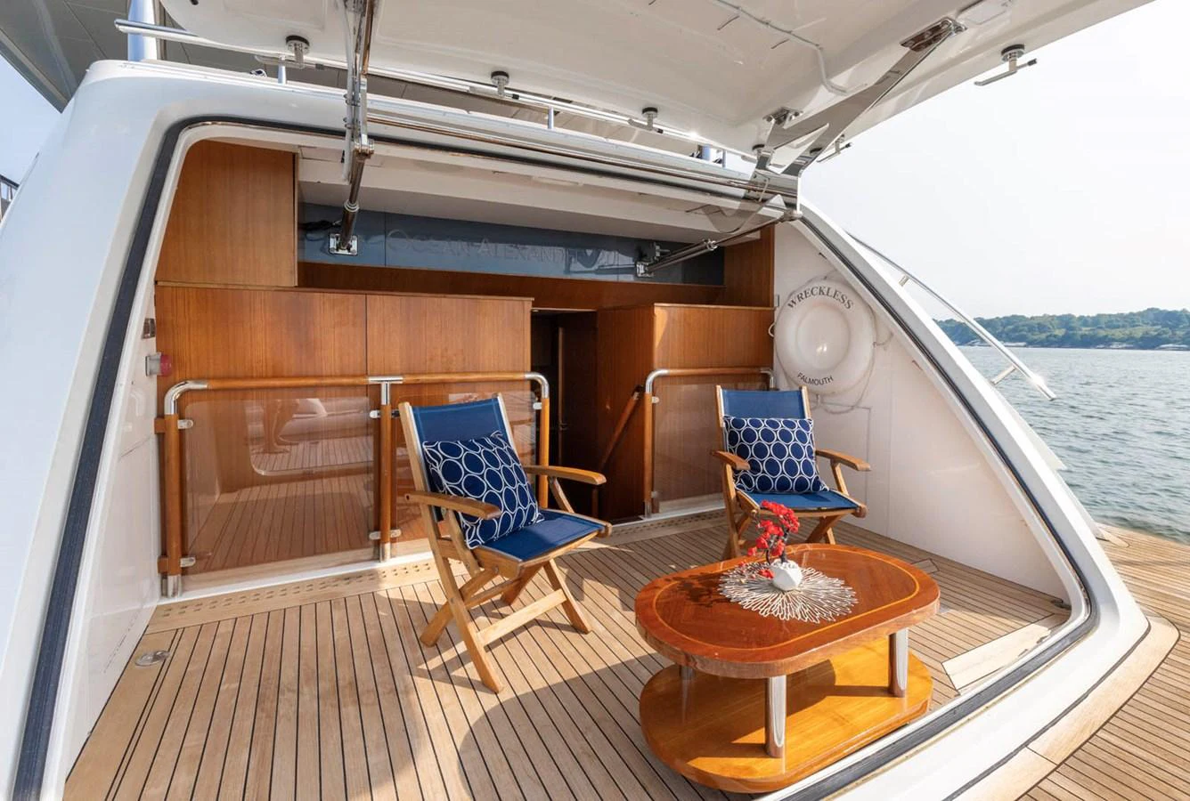 The aft deck offers a cozy seating area with wooden chairs and a table, perfect for enjoying the view. aboard WRECKLESS Yacht for Sale