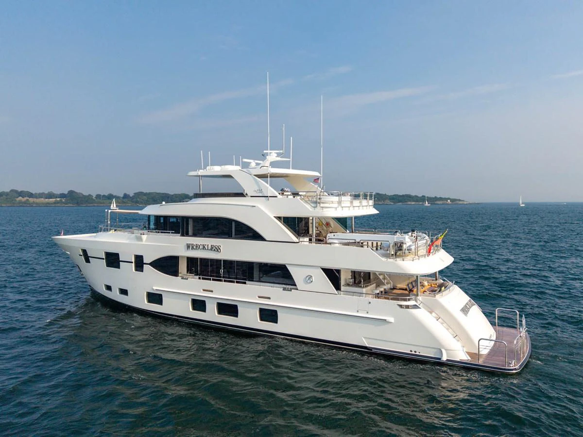 A luxurious yacht cruising on calm waters under a clear blue sky. aboard WRECKLESS Yacht for Sale