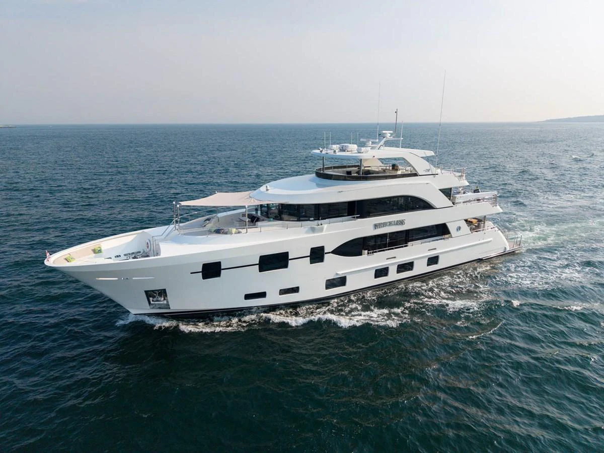 A sleek, modern yacht cruising on open waters under a clear sky. aboard WRECKLESS Yacht for Sale