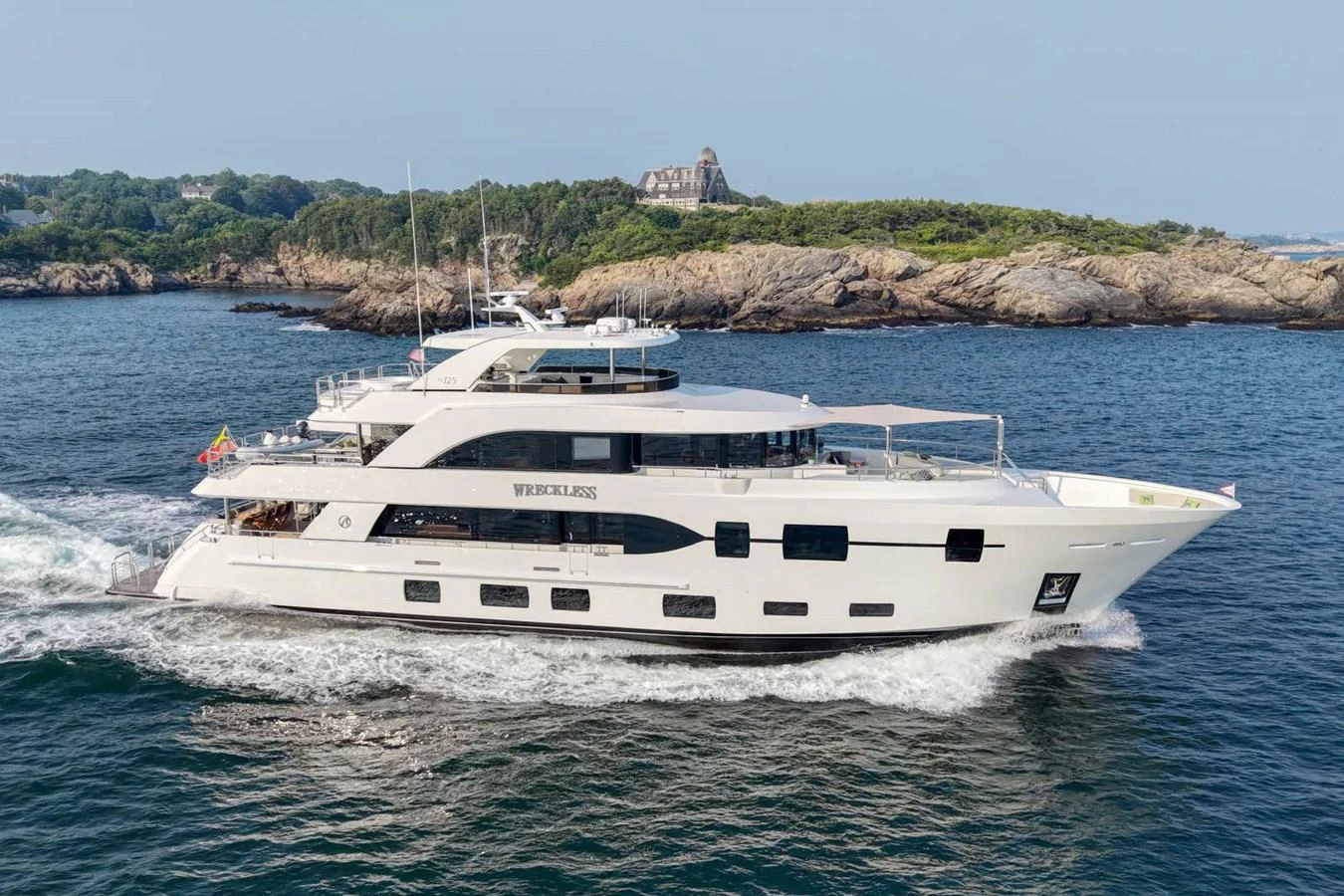 A sleek and modern yacht cruises along a scenic coastline, showcasing its elegant design and spacious decks. aboard WRECKLESS Yacht for Sale