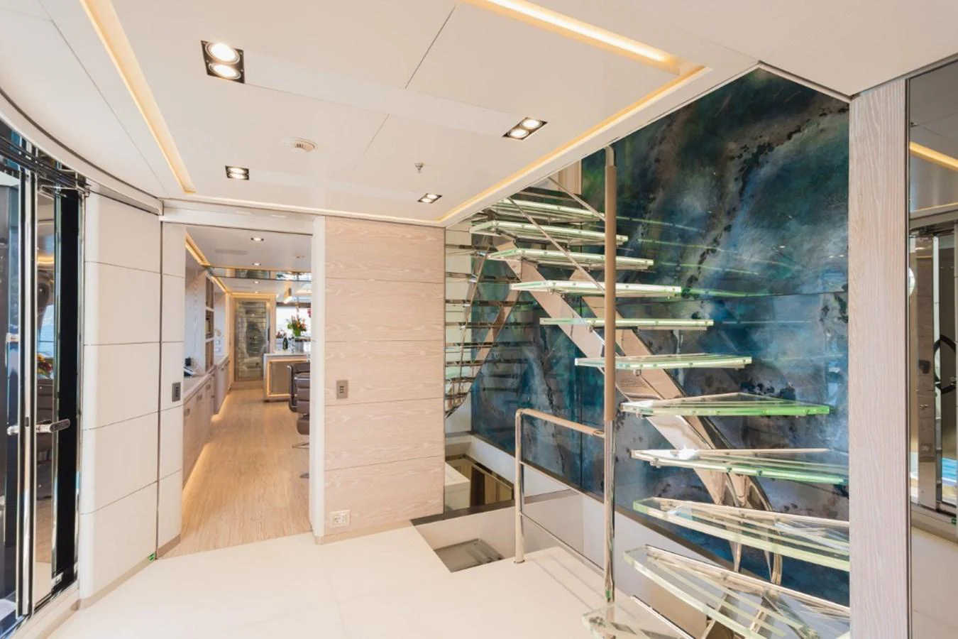 The yacht's interior features a stunning modern staircase with glass steps and a striking wall design. aboard PICK UP Yacht for Sale