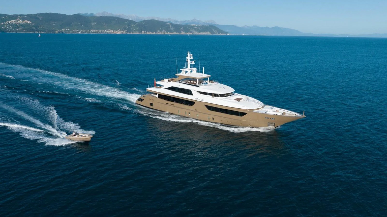 A luxurious yacht cruises through clear blue waters, accompanied by a tender. aboard PICK UP Yacht for Sale