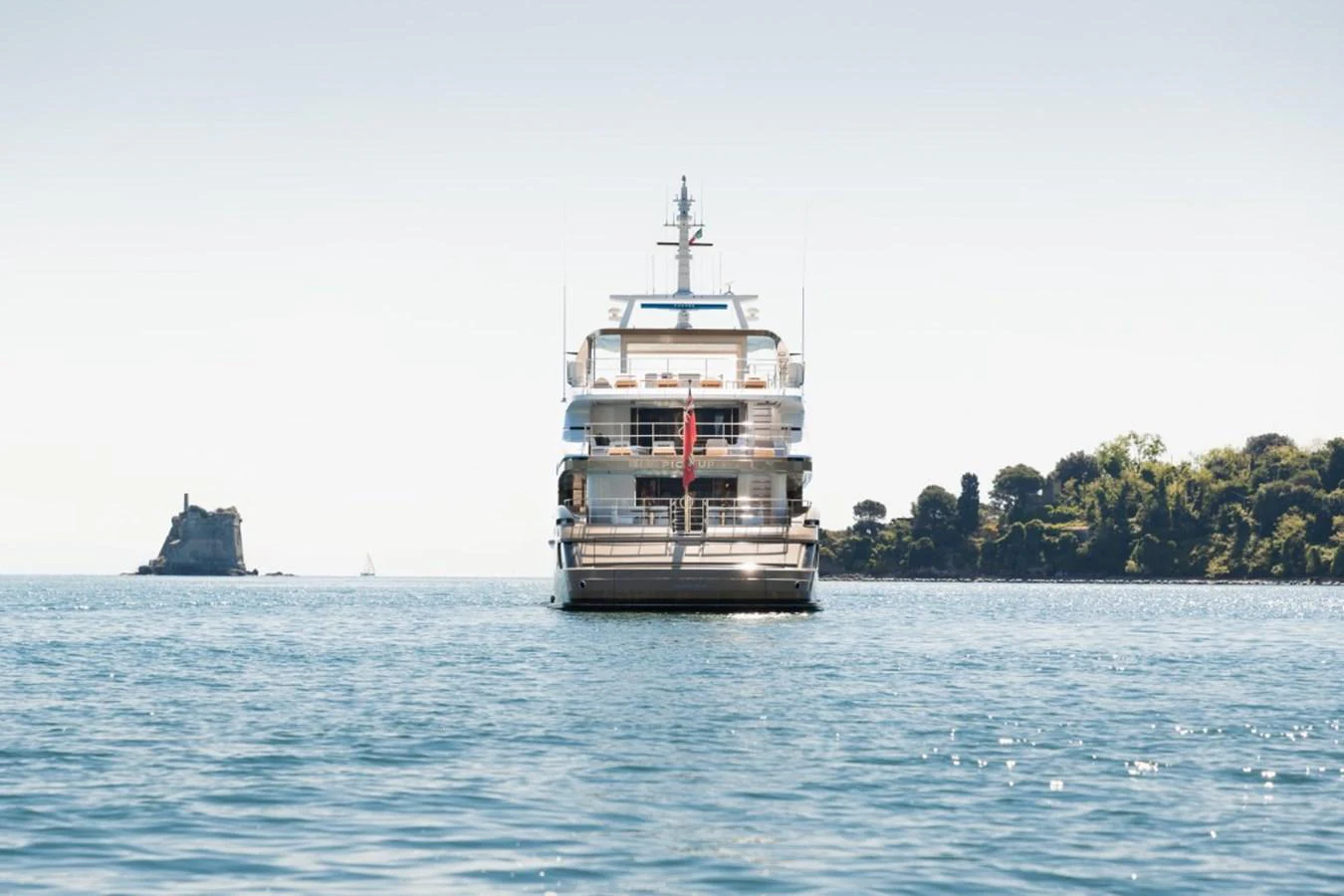 A luxurious yacht is anchored on calm waters with a scenic coastal backdrop. aboard PICK UP Yacht for Sale