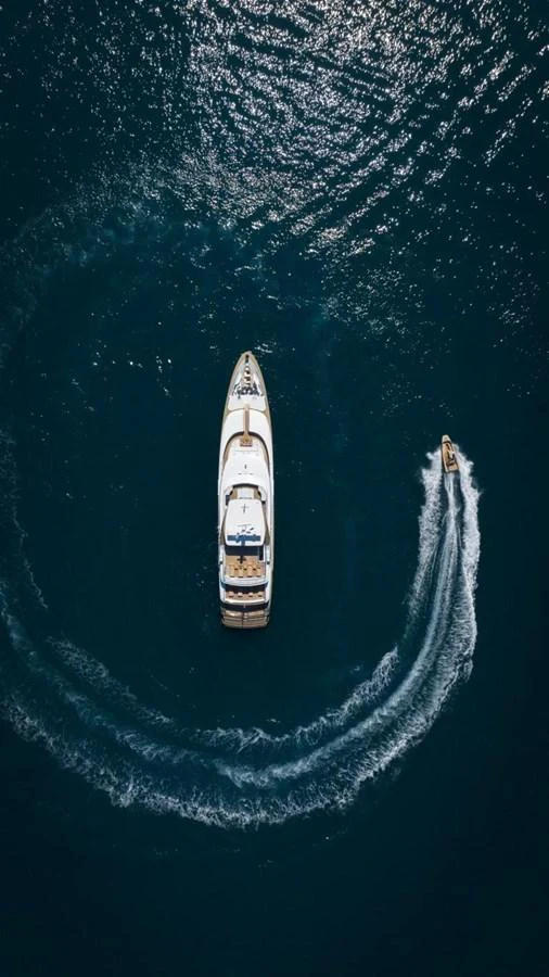 An aerial view of a sleek yacht cruising through the water with a tender nearby. aboard PICK UP Yacht for Sale