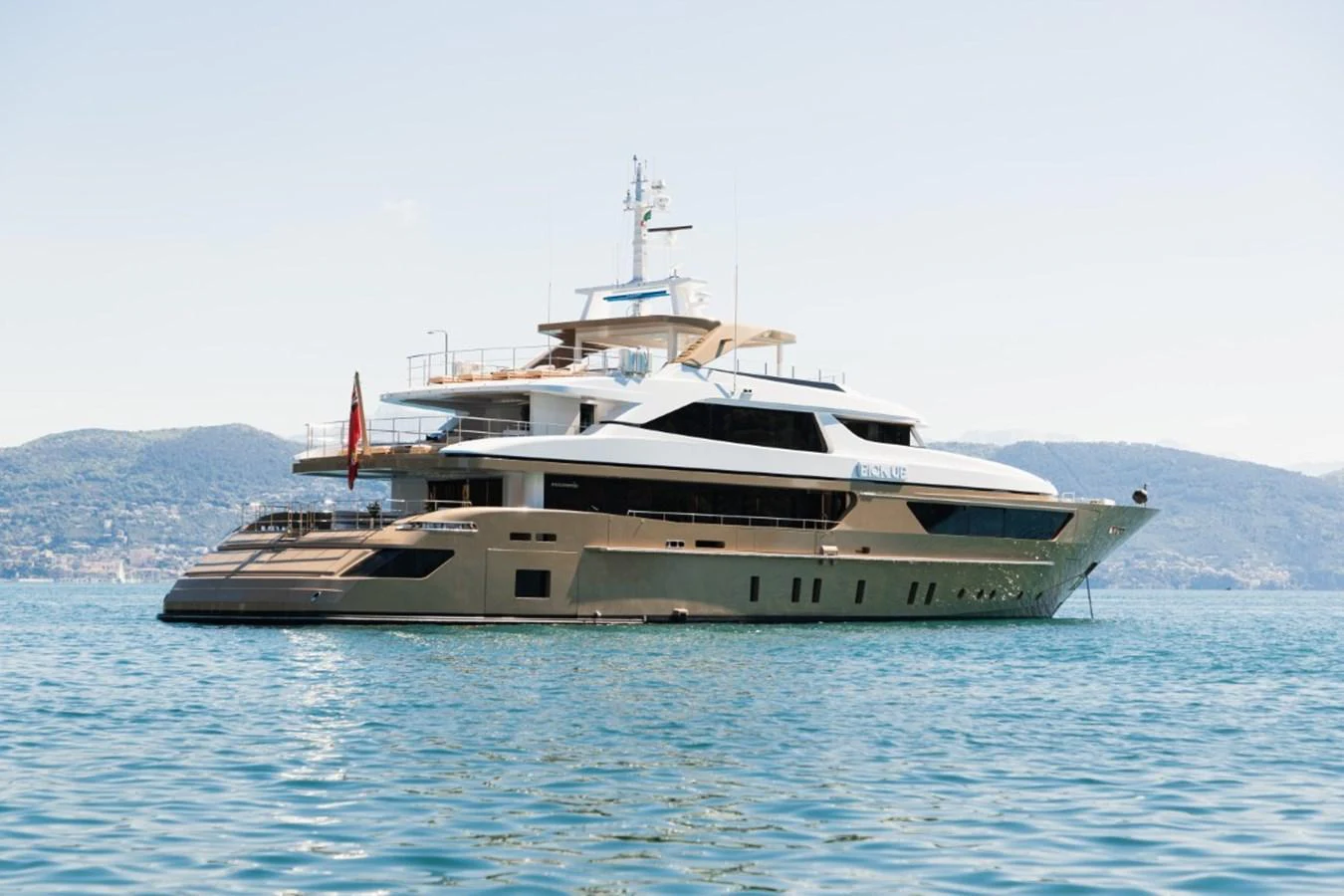 A luxurious yacht is anchored on calm waters with a scenic backdrop of hills. aboard PICK UP Yacht for Sale
