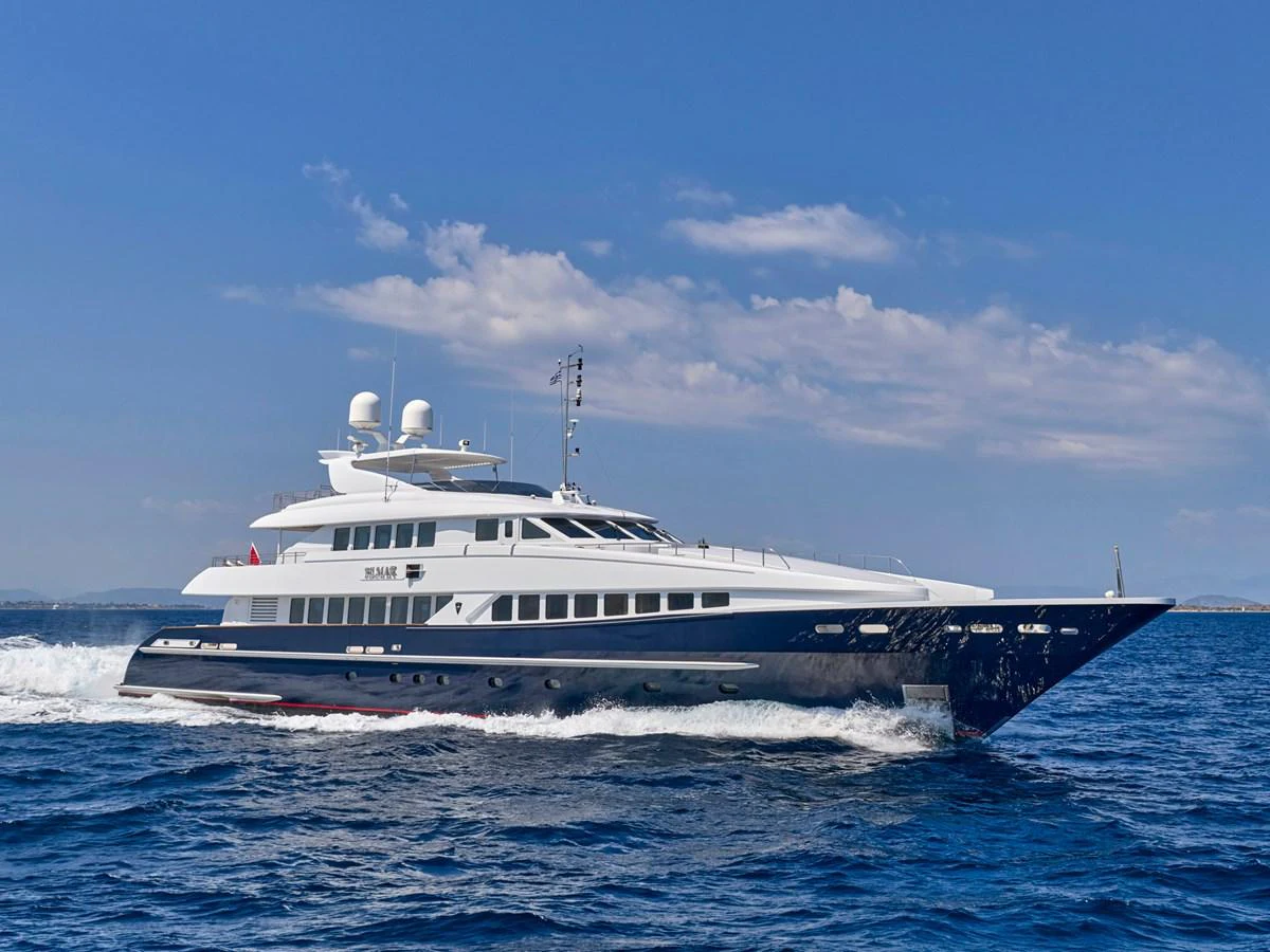 A sleek and elegant yacht cruises through the open sea under a clear blue sky. aboard BILMAR Yacht for Sale
