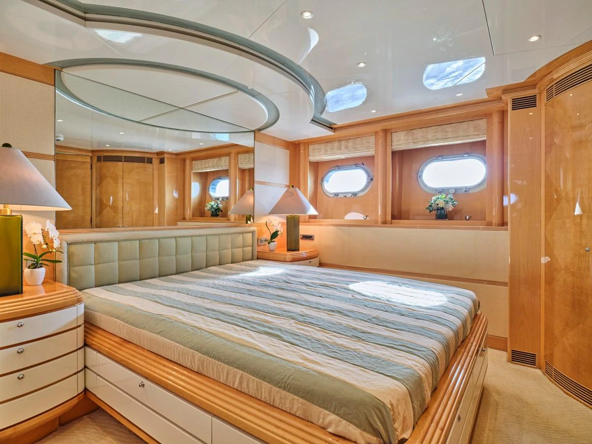 The master stateroom features a spacious bed with elegant wood finishes and ample natural light. aboard BILMAR Yacht for Sale