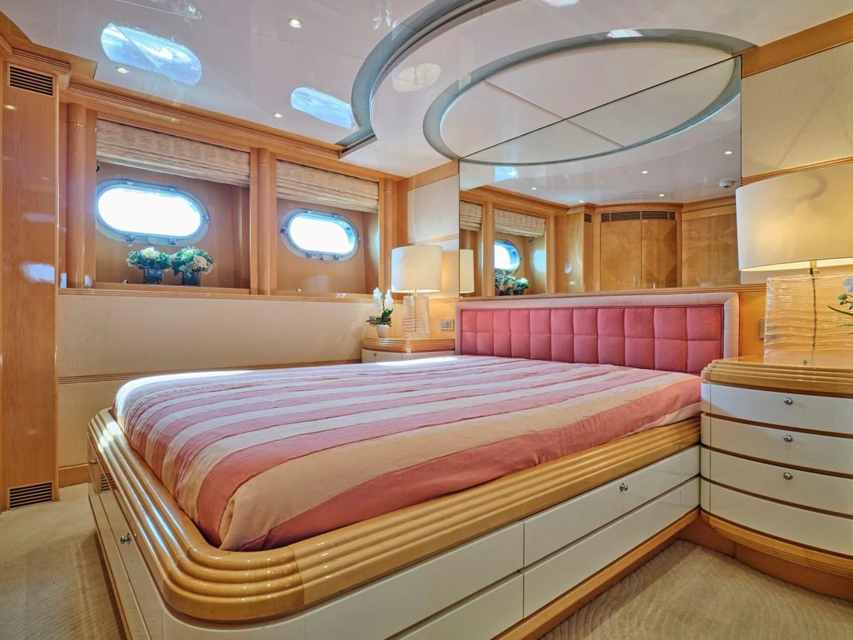 The stateroom features a luxurious bed with elegant wood and mirrored accents, creating a serene and inviting atmosphere. aboard BILMAR Yacht for Sale