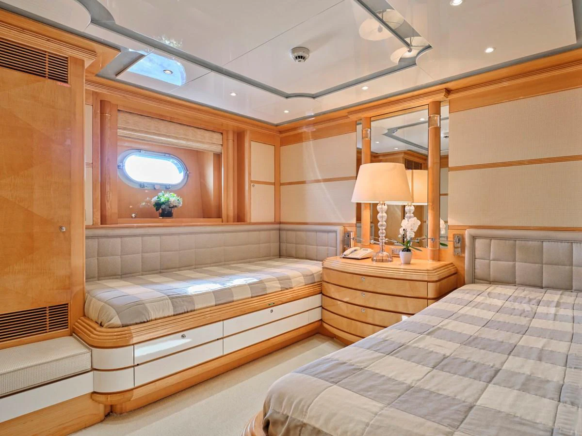 The guest stateroom features a cozy bed, a comfortable seating area, and elegant wooden finishes. aboard BILMAR Yacht for Sale