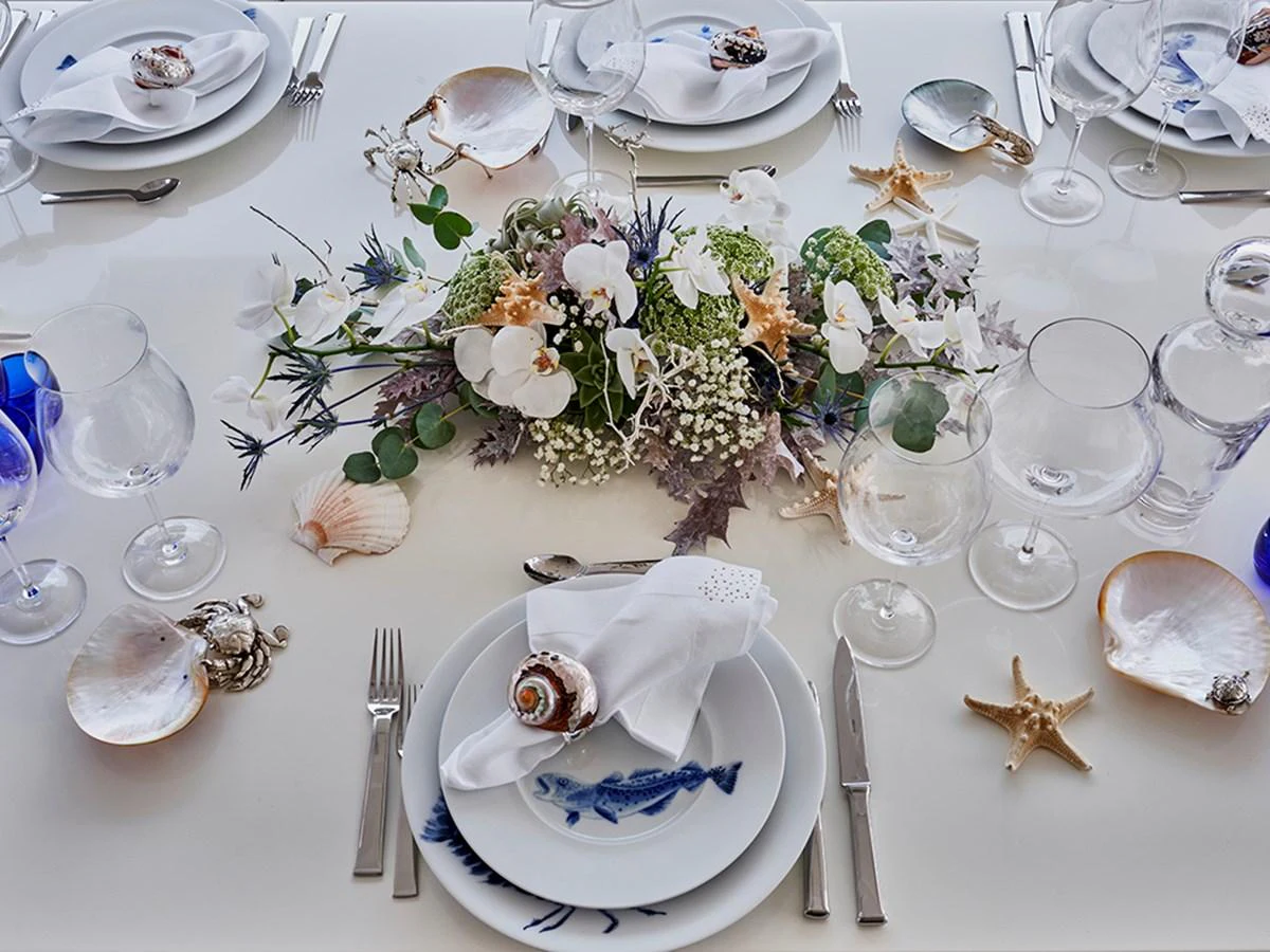 A beautifully set dining table with elegant floral arrangements and sea-themed decorations. aboard UHUD Yacht for Sale