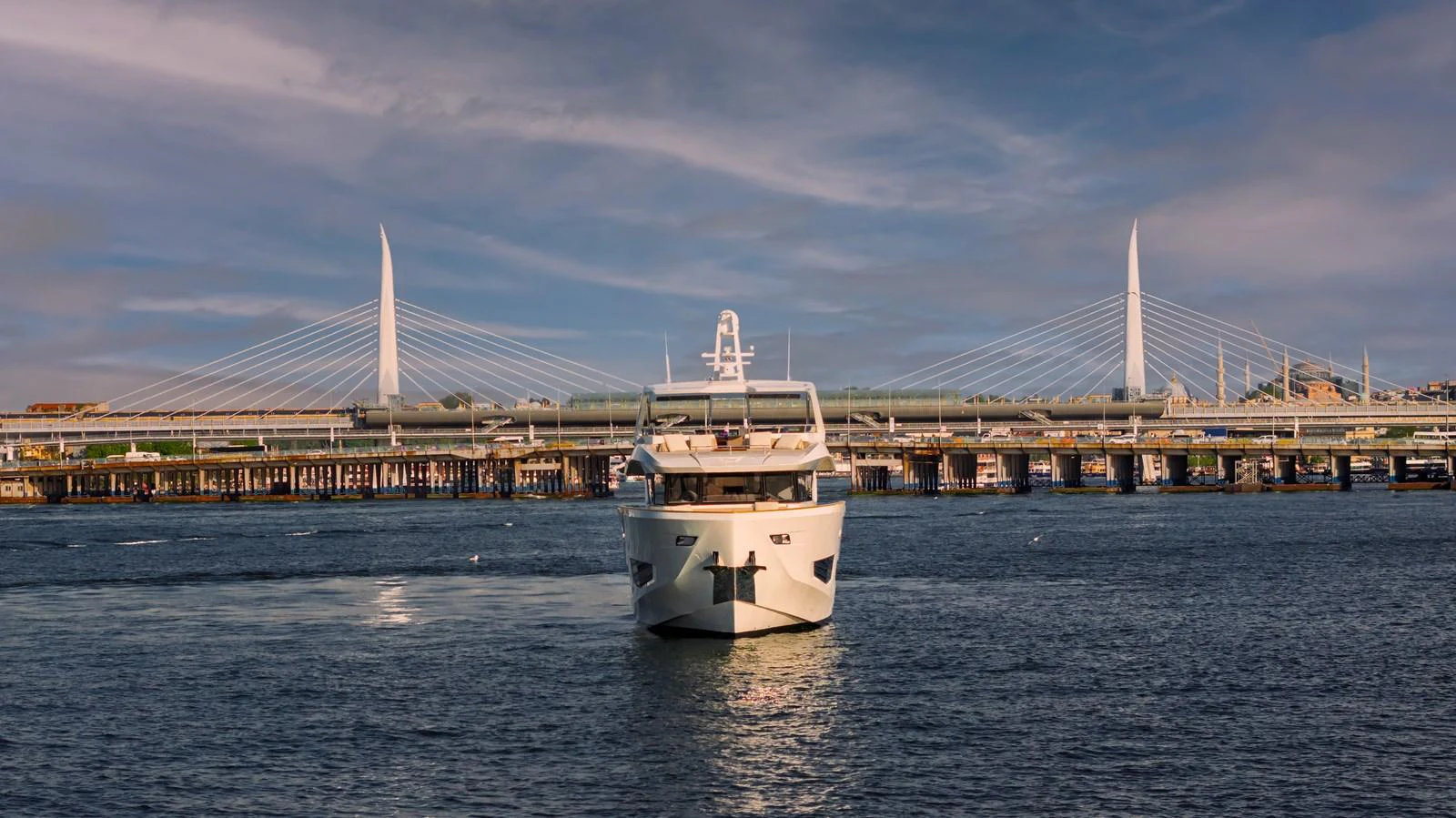 A sleek yacht is seen approaching from the water with a scenic bridge in the background. aboard NUMARINE 27XP#6 Yacht for Sale