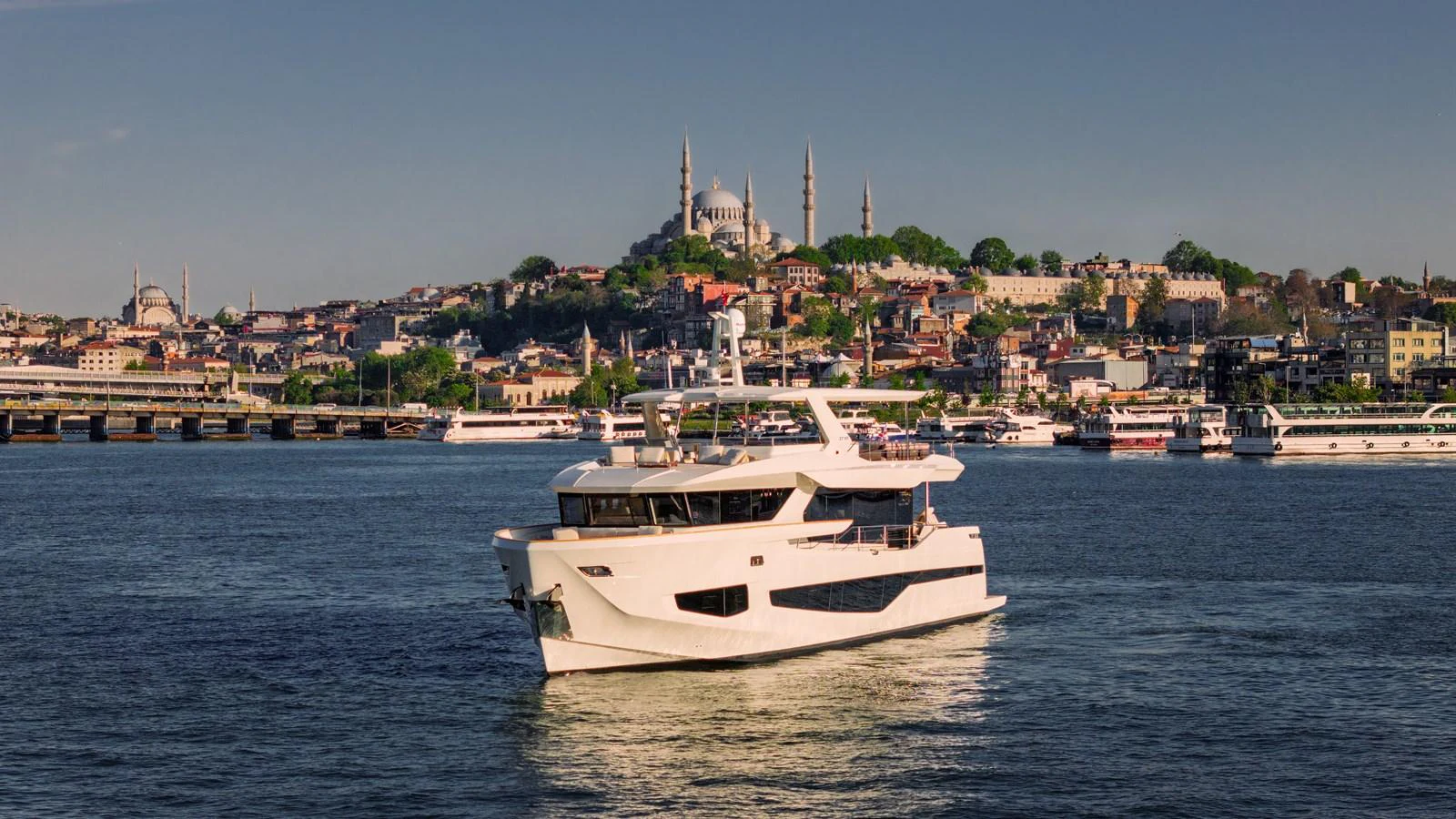 A sleek, modern yacht cruises against a picturesque cityscape backdrop. aboard NUMARINE 27XP#6 Yacht for Sale